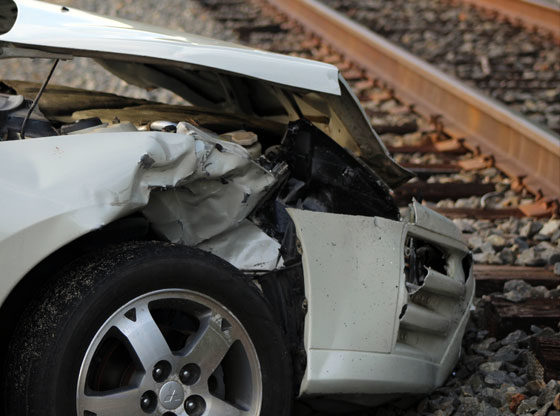 Cars collide sending one into train tracks