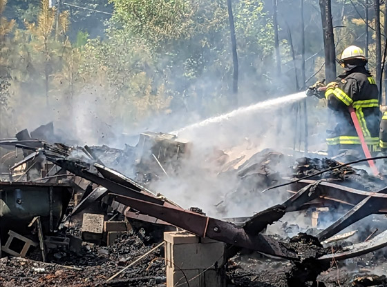 Firefighters stop mobile home fire from spreading into woods