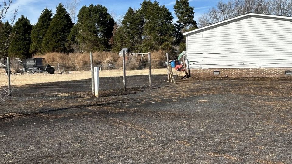 One in custody after burning belongings threaten neighboring home